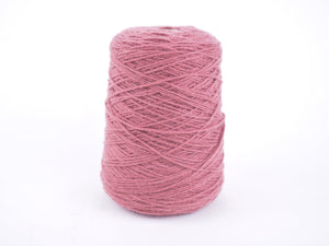 A single cone of dusty pink yarn wound tightly, standing upright on a seamless white background.